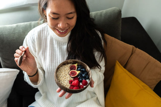 woman eating a healthy breakfast with gut friendly foods to support gut health and overall skin wellness